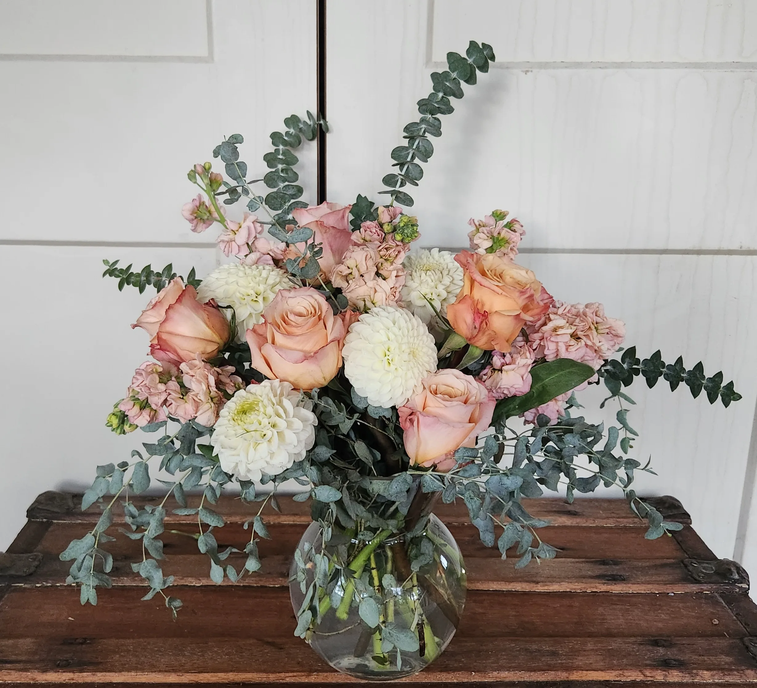 Pink and white floral arrangement in glass vase.
