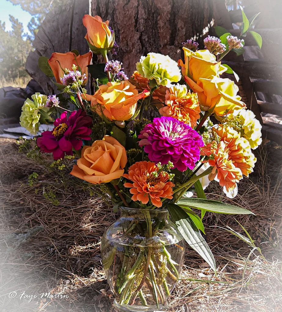 Colorful flowers in a clear glass vase outdoors.