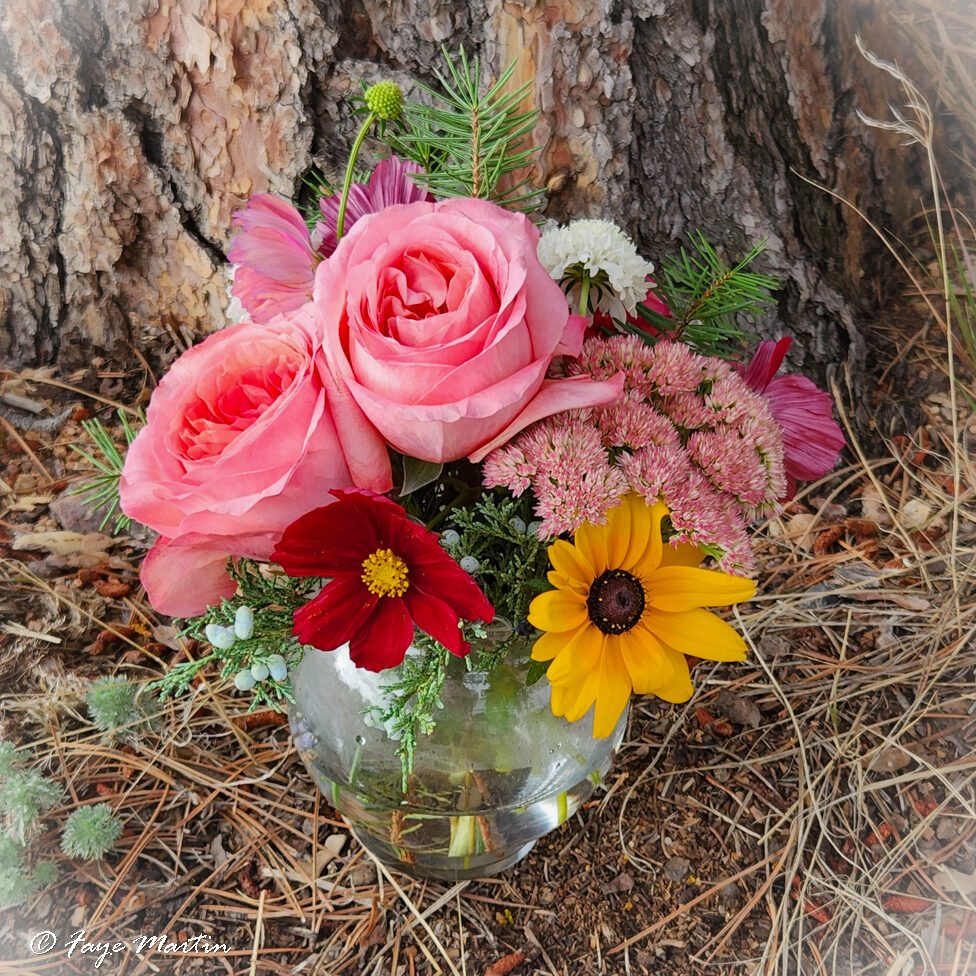 Bouquet with roses and wildflowers by tree bark.